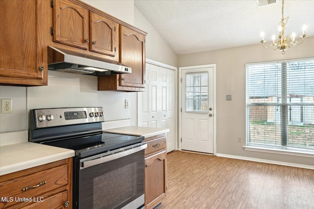 kitchen with under cabinet range hood, stainless steel electric range oven, and brown cabinetry