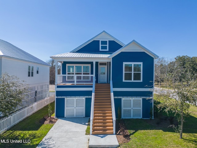 beach home featuring metal roof, a front lawn, stairway, and a porch