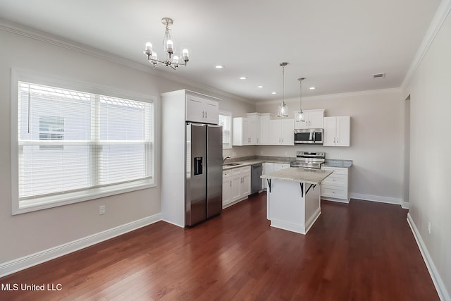 kitchen with a center island, pendant lighting, stainless steel appliances, white cabinetry, and a sink