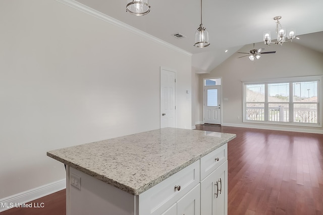 kitchen with light stone counters, a kitchen island, white cabinetry, open floor plan, and decorative light fixtures