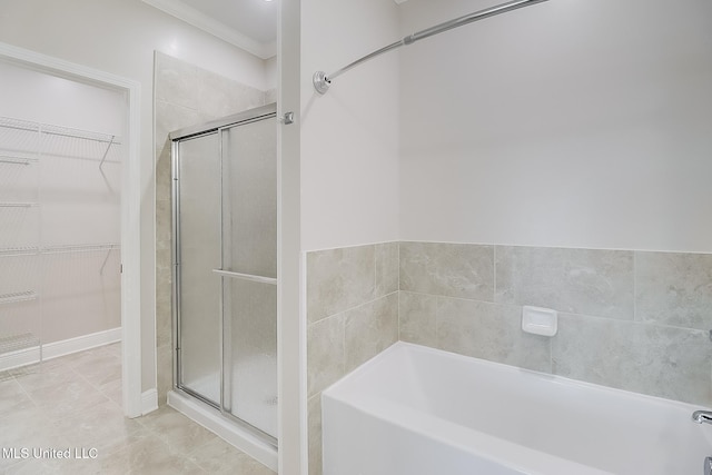 bathroom with ornamental molding, a walk in closet, a garden tub, and a shower stall