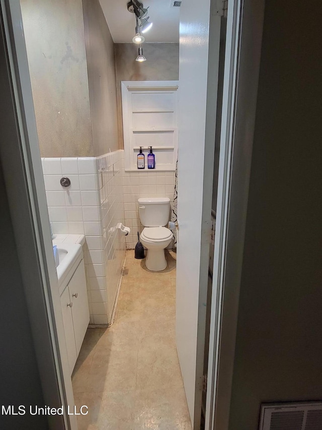 201 Seymour Dr, Indianola, MS 38751 - half bath featuring tile patterned floors, toilet, vanity, visible vents, and tile walls