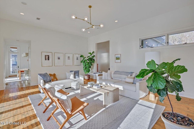 living room with light hardwood / wood-style floors, an inviting chandelier, and a wealth of natural light