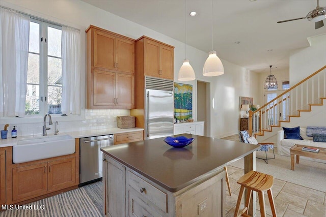 kitchen with a kitchen island, decorative backsplash, sink, decorative light fixtures, and appliances with stainless steel finishes