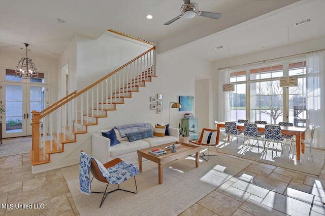 living room featuring french doors and ceiling fan with notable chandelier