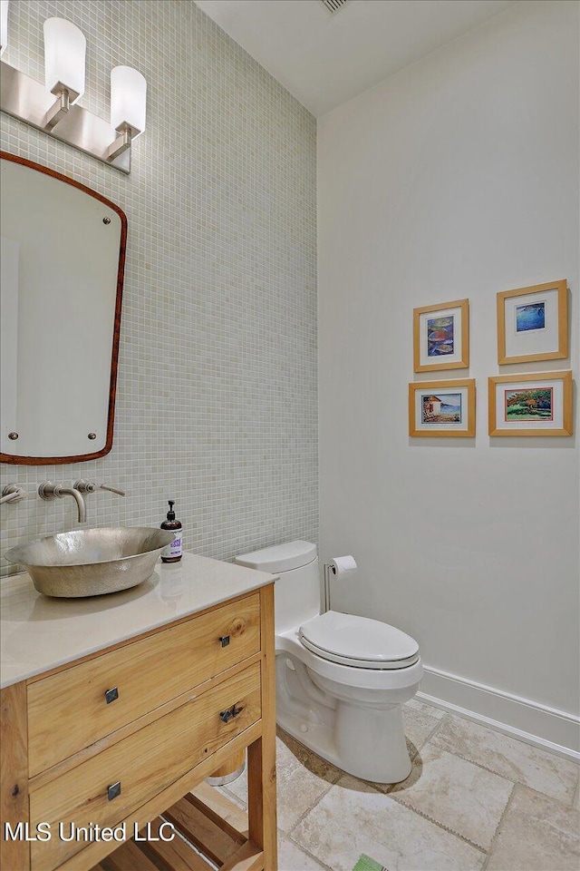 bathroom featuring vanity, toilet, and tile walls