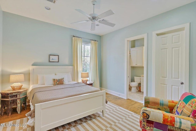 bedroom with light hardwood / wood-style flooring, ceiling fan, and ensuite bath