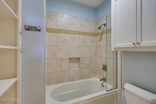 bathroom with tiled shower / bath combo and toilet