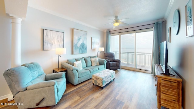 living area with crown molding, wood finished floors, a ceiling fan, and ornate columns