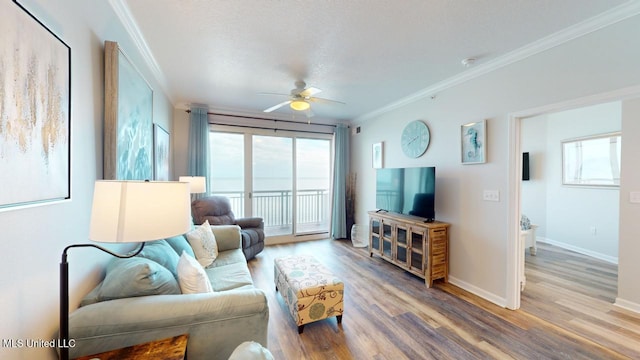 living room with baseboards, ceiling fan, ornamental molding, wood finished floors, and a textured ceiling