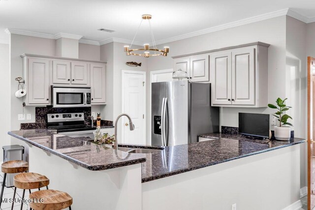 807 Woodglen Dr, Ocean Springs, MS 39564 - kitchen featuring appliances with stainless steel finishes, a sink, a peninsula, dark stone countertops, and a chandelier