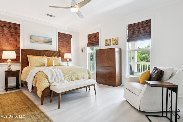 bedroom featuring ceiling fan, light wood-style floors, visible vents, and crown molding