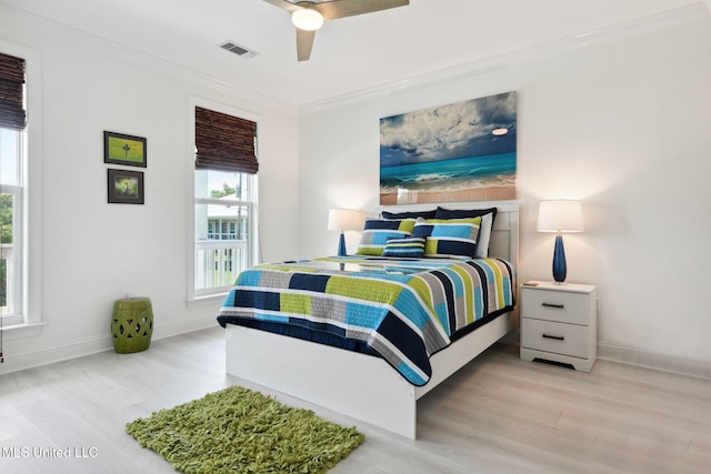 bedroom with visible vents, crown molding, baseboards, and wood finished floors