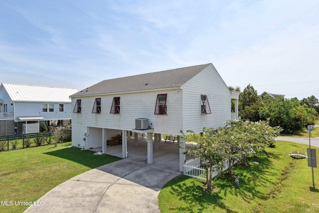 view of front of home featuring concrete driveway, roof with shingles, fence, a carport, and a front yard