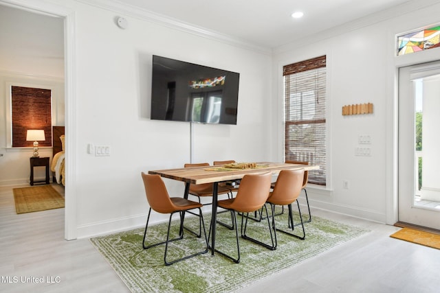 dining room featuring a healthy amount of sunlight, light wood-type flooring, and crown molding