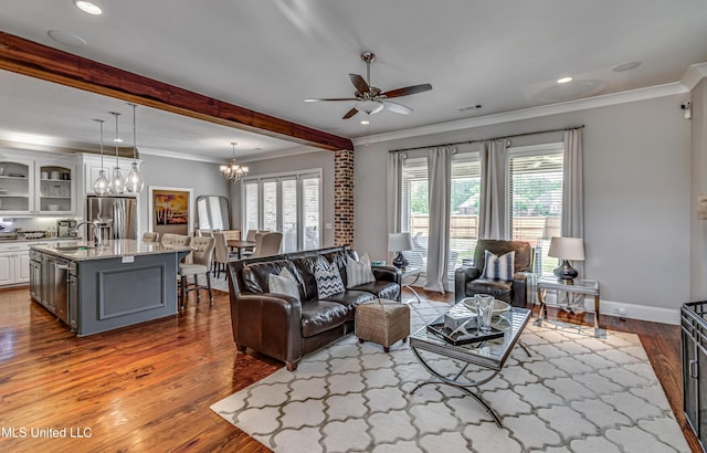 living area with crown molding, ceiling fan with notable chandelier, wood finished floors, and a healthy amount of sunlight