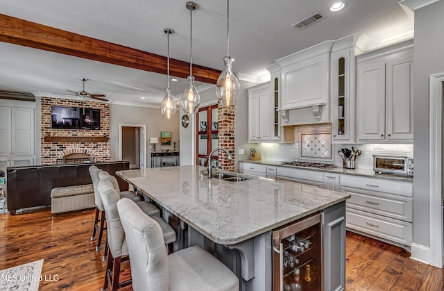 kitchen featuring visible vents, a ceiling fan, wine cooler, stainless steel gas cooktop, and a sink