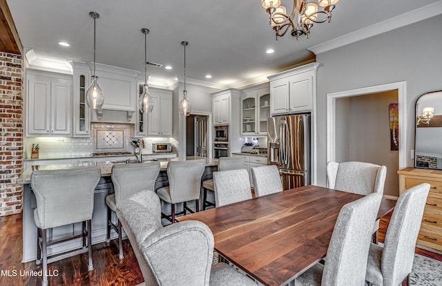 dining area featuring crown molding, dark wood finished floors, a chandelier, and visible vents