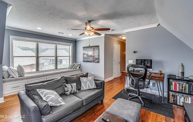 living room with ceiling fan, visible vents, wood finished floors, baseboards, and ornamental molding