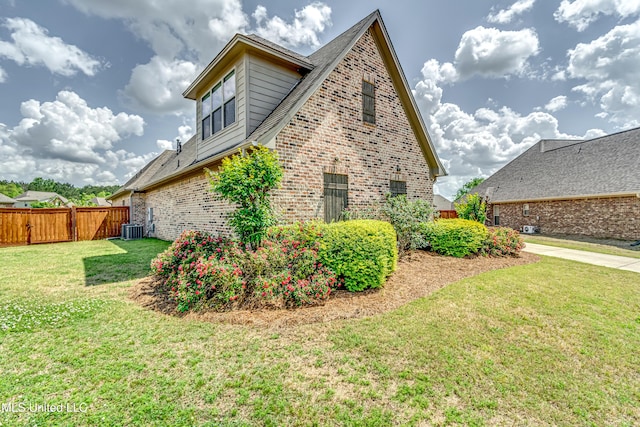 view of side of home with a yard, brick siding, fence, and cooling unit