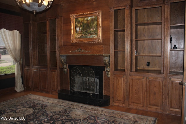 unfurnished living room with dark hardwood / wood-style floors, a tile fireplace, and wood walls