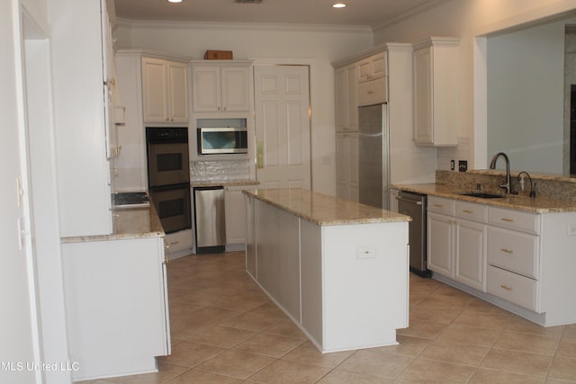 kitchen with kitchen peninsula, sink, light stone countertops, white cabinets, and appliances with stainless steel finishes