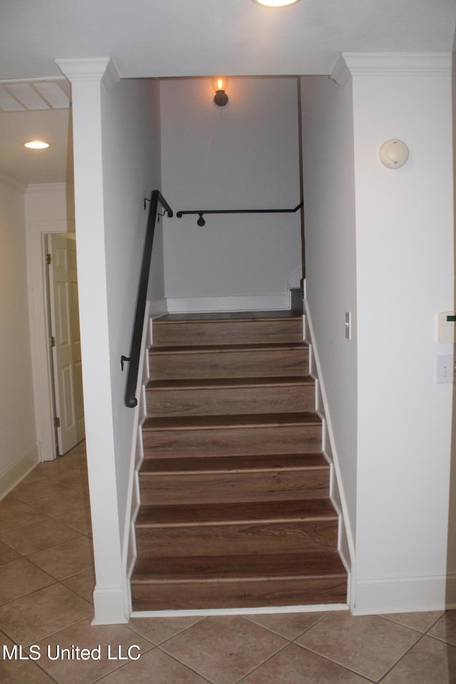 stairs with ornamental molding and tile patterned floors