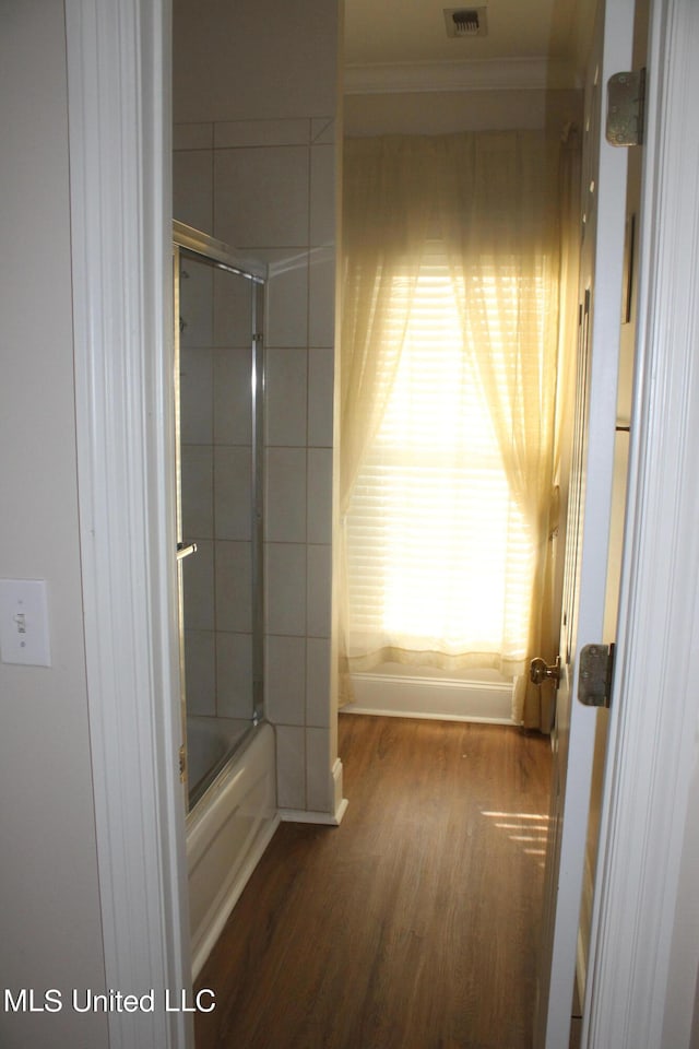 bathroom with hardwood / wood-style floors and enclosed tub / shower combo