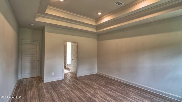 empty room featuring ornamental molding, baseboards, visible vents, dark wood-type flooring, and a tray ceiling