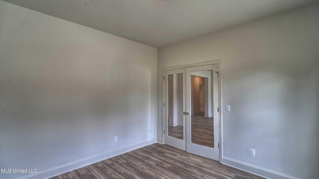 empty room featuring baseboards, dark wood-style flooring, and french doors