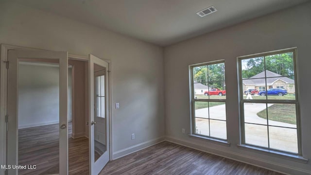spare room featuring visible vents, baseboards, french doors, and dark wood finished floors