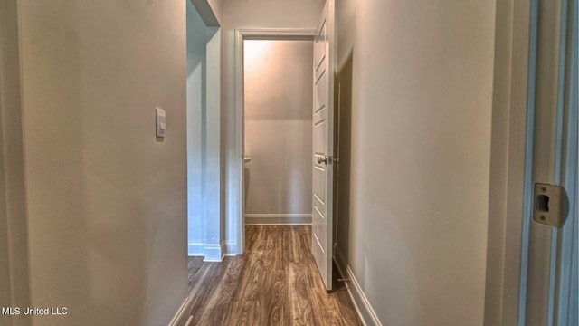 hall with baseboards and dark wood-type flooring