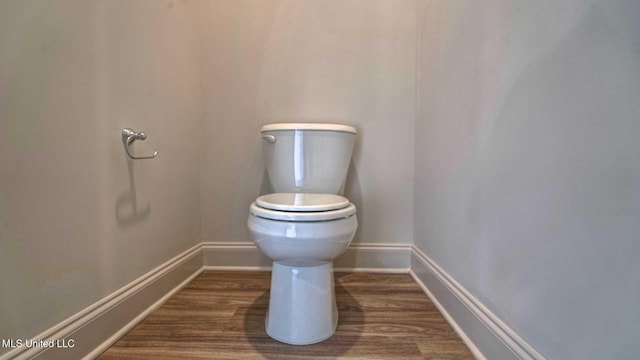 bathroom featuring toilet, wood finished floors, and baseboards