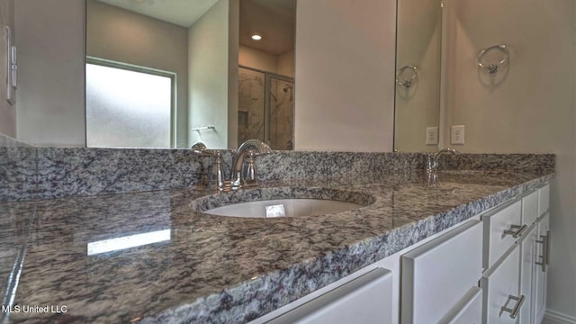 bathroom featuring double vanity, a shower stall, and a sink