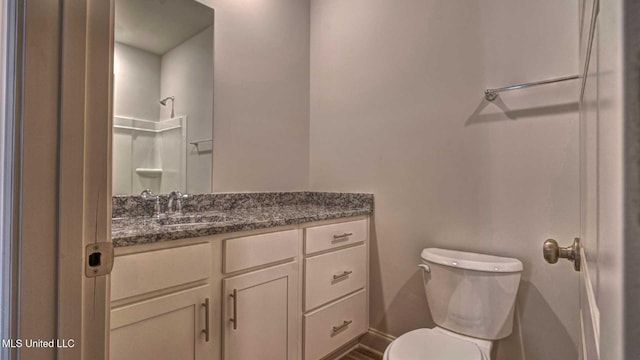 bathroom with toilet, a shower, and vanity