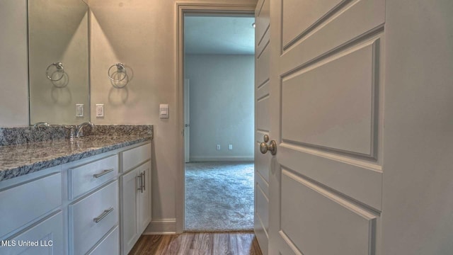 bathroom with wood finished floors, vanity, and baseboards