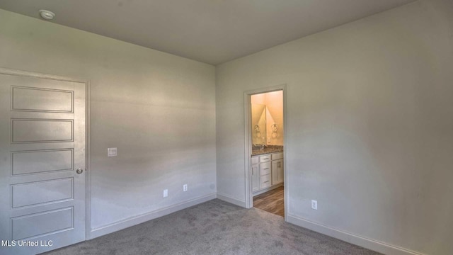 unfurnished bedroom with connected bathroom, carpet flooring, and baseboards