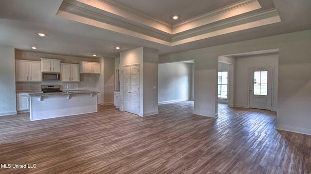 kitchen with stainless steel appliances, baseboards, a raised ceiling, open floor plan, and crown molding