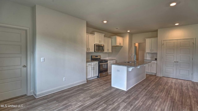 kitchen featuring white cabinetry, dark stone countertops, appliances with stainless steel finishes, and dark wood-style floors