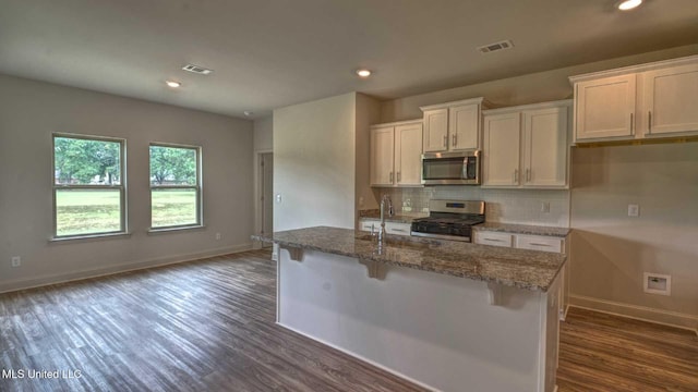 kitchen with a sink, appliances with stainless steel finishes, visible vents, baseboards, and dark wood-type flooring