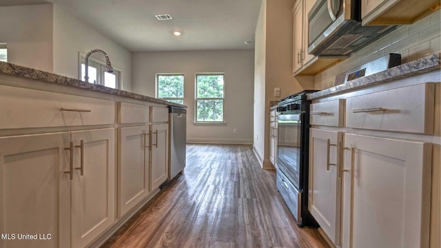 kitchen with tasteful backsplash, appliances with stainless steel finishes, baseboards, visible vents, and dark wood-type flooring