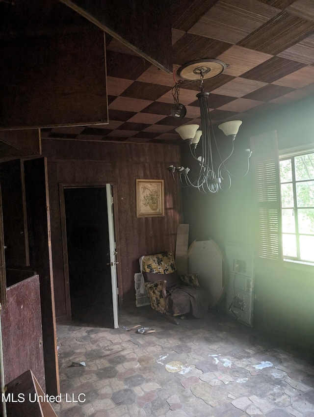 unfurnished dining area with a chandelier and wooden walls