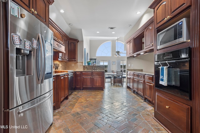 kitchen featuring light stone countertops, kitchen peninsula, stainless steel appliances, and tasteful backsplash