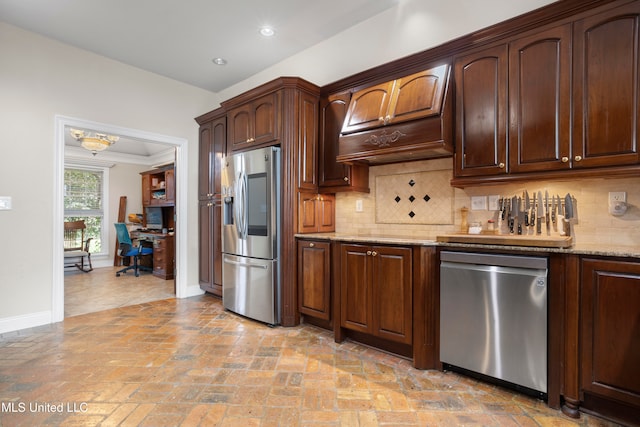 kitchen with decorative backsplash, light stone counters, premium range hood, and appliances with stainless steel finishes