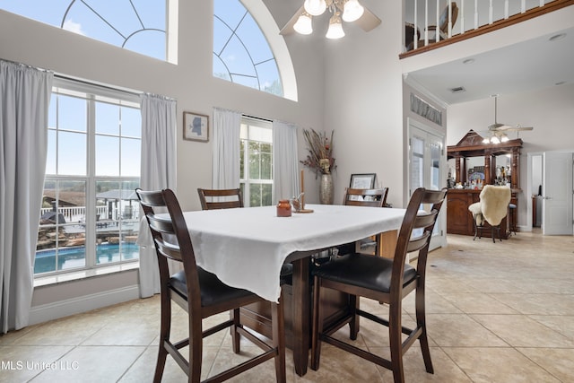 tiled dining area with a high ceiling, ceiling fan, and a healthy amount of sunlight