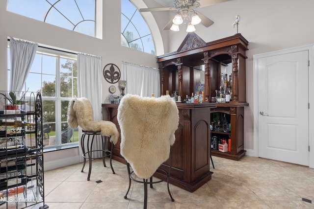 interior space with ceiling fan, light tile patterned flooring, and indoor bar