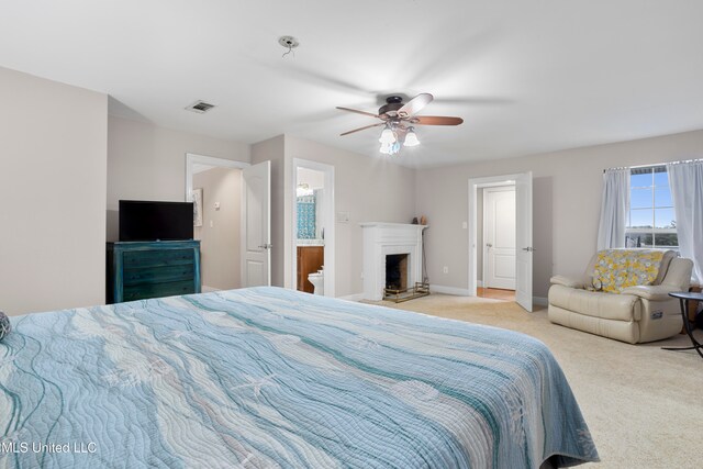 carpeted bedroom with ensuite bathroom and ceiling fan