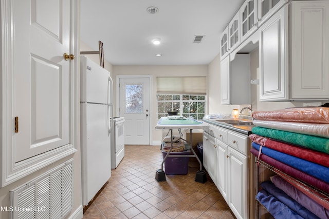 kitchen with tile patterned floors, white appliances, white cabinetry, and sink