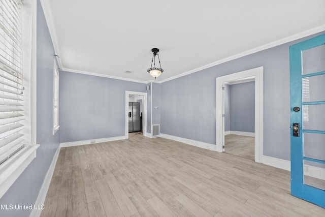 spare room with baseboards, wood finished floors, and crown molding