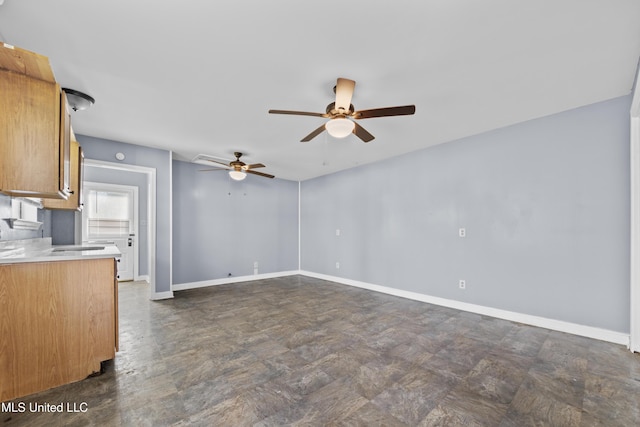 unfurnished living room featuring baseboards and ceiling fan